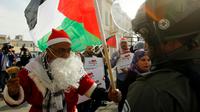 Un manifestant palestinien habillé en père Noël s'oppose à un membre des forces de l'ordre israélienne à Bethléem, en Cisjordanie occupée, le 23 décembre 2017 [Musa AL SHAER / AFP]