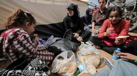 Des manifestants palestiniens mangent près d'une tente le 30 mars 2018 lors d'une manifestation près de la frontière avec Israël, dans le sud de la bande de Gaza [SAID KHATIB / AFP]