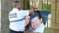 Un officier de police tient le 20 juin 2016 à Pézénas dans l'Hérault une photographie de Jessica Schneider et Jean-Baptiste Salvaing, victimes d'un assassinat jihadiste à Magnanville, le 13 juin 2016 [SYLVAIN THOMAS / AFP/Archives]