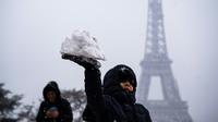 Un enfant joue avec de la neige devant la Tour Eiffel, le 5 février 2018 à Paris. [Lionel BONAVENTURE / AFP/Archives]