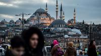 Des piétons traversent le pont de Galata à Istanbul, le 27 janvier 2018, avec la mosquée de Suleymaniye en arrière-plan [YASIN AKGUL / AFP/Archives]
