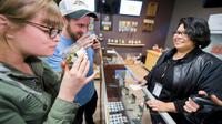 Des touristes venus de d'Arizona sentent des têtes de cannabis dans un magasin de Desert Hot Springs, en Californie, le 1er janvier 2018. [Robyn Beck / AFP]