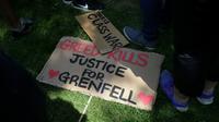 "La cupidité tue", clame cette pancarte sur le sol, lors d'une manifestation le 21 juin 2017 près de la Grenfell Tower de Londres, où au moins 80 personnes ont trouvé la mort dans le gigantesque incendie du 14 juin [Daniel LEAL-OLIVAS / AFP]