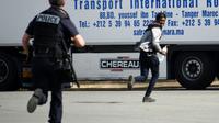 Un policier poursuit un jeune homme suspecté d'être un migrant, dans les environs de Calais le 5 juillet 2017 [DENIS CHARLET / AFP]