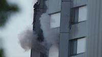Une main tenant un tissu apparaît à la fenêtre d'un appartement d'une tour d'habitation ravagée par un incendie, le 14 juin 2017 à Londres [Daniel LEAL-OLIVAS / AFP]