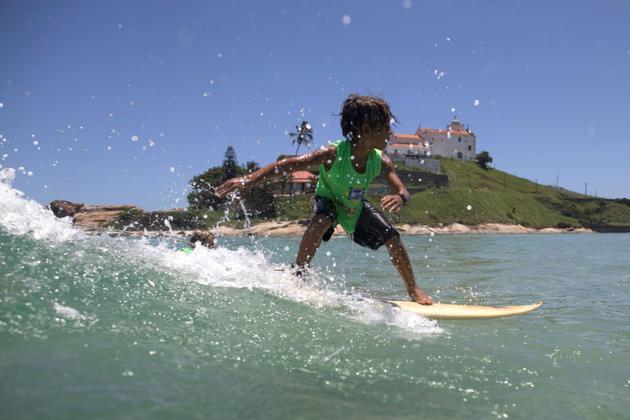Daniel Cortinhas, 9 ans, surfe sur une vague au large de Saquarema, dans l'Etat de Rio, au Brésil, le 29 novembre 2017 [LEO CORREA / AFP]