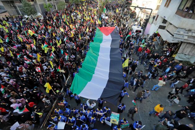 Des partisans du mouvement libanais Hezbollah défilent avec un drapeau palestinien géant à Beyrouth le 11 décembre 2017 [Joseph EID / AFP]