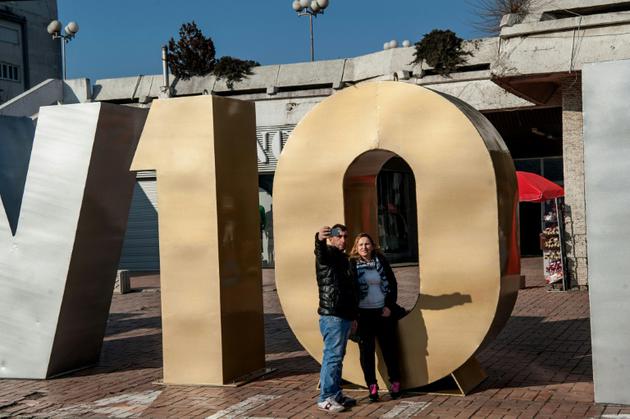 Un couple prend un selfie devant le monument à la "Renaissance" érigé pour le 10e anniversaire de l'indépendance du Kosovo à Pristina, le 17 février 2018 [Armend NIMANI / AFP]