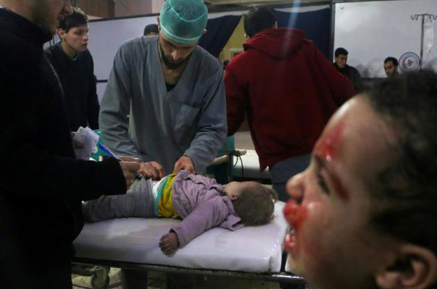 Des secouristes soignent un enfant blessé alors qu'un autre pleure dans une clinique de fortune à Douma, dans la Ghouta orientale, bombardée par le régime, le 22 février 2018 [Hamza AL-AJWEH / AFP]