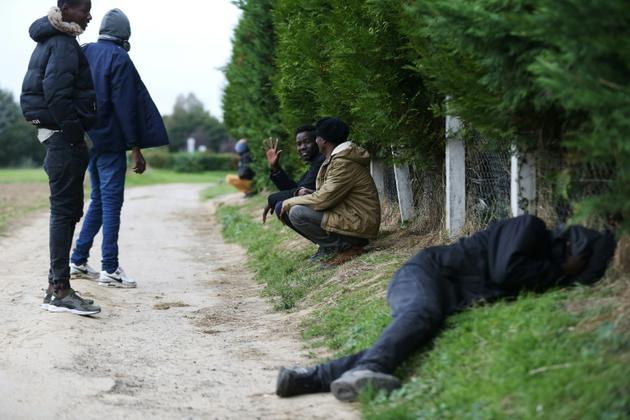 Des migrants dorment ou attendent sur le bord d'un chemin à Ouistreham, près de Caen, le 5 octobre 2017 [CHARLY TRIBALLEAU / AFP/Archives]