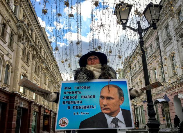 Une militante distribue des tracts en faveur de Vladimir Poutine dans une rue de Moscou, le 16 mars 2018 [Yuri KADOBNOV / AFP]