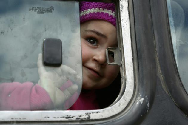 Une fillette syrienne à la fenêtre d'un bus dans un convoi transportant des rebelles et des civils dans le village de Qalaat al-Madiq, dans la province de Hama le 25 mars 2018, après leur évacuation de la Ghouta orientale, aux portes de Damas [Zein Al RIFAI / AFP]