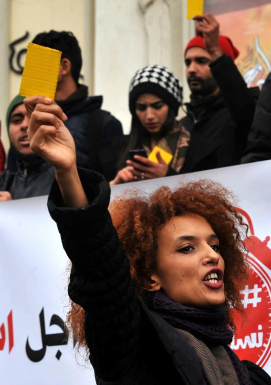 Une manifestante brandit un carton jaune contre le gouvernement lors d'une manifestation à Tunis le 12 janvier 2018 contre les mesures d'austérité. [Sofiene HAMDAOUI / AFP]