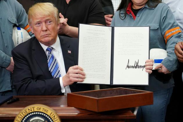 Le président américain Donald Trump montre le document qu'il vient de signer instaurant des taxes sur les importations d'acier et d'aluminium, le 8 mars 2018 à la Maison Blanche, à Washington [MANDEL NGAN / AFP]