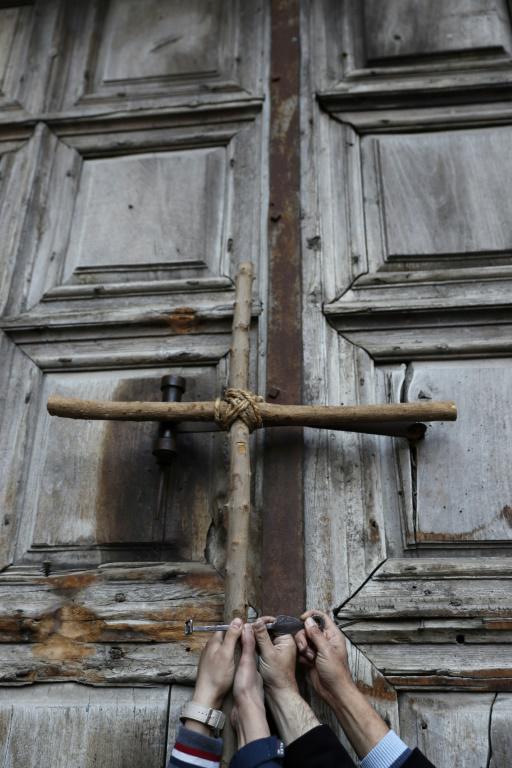 Des fidèles tiennent une croix devant le Saint-Sépulcre, lieu le plus saint du christianisme à Jérusalem, après sa fermeture, le 27 février 2018  [Thomas COEX / AFP]