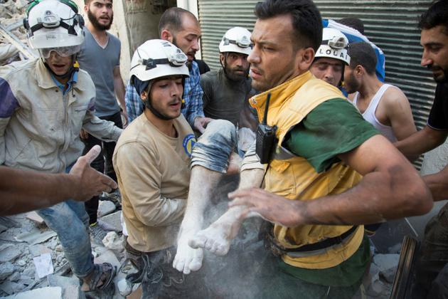 Les "casques blancs" syriens transportent un corps après un raid aérien à Alep le 23 juillet 2016 [KARAM AL-MASRI / AFP/Archives]