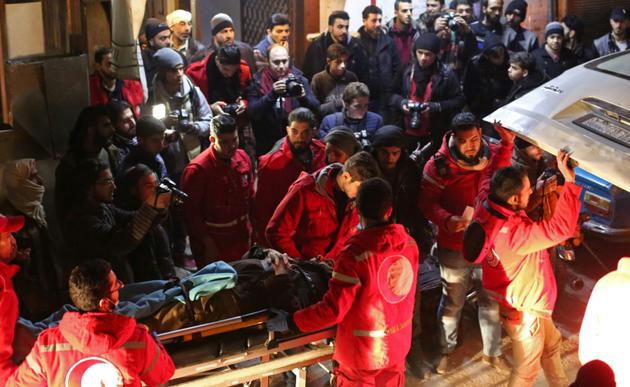 Des volontaires du Croissant-rouge syrien transportent un malade dans une ambulance pour l'évacuer de Douma vers Damas où il doit recevoir des soins, tard le 28 décembre 2017 [Amer ALMOHIBANY / AFP]
