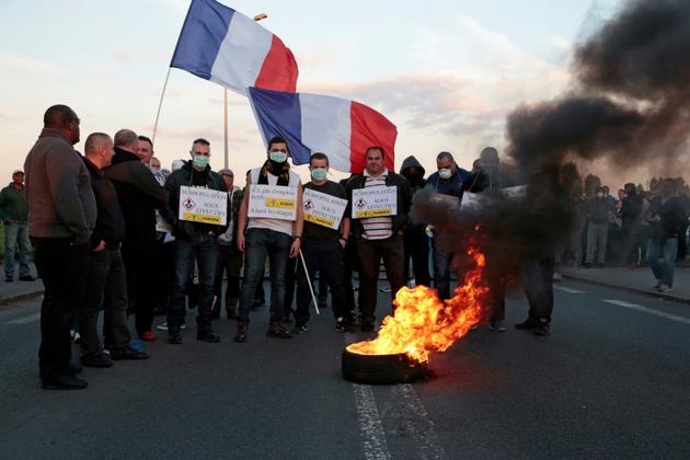 Des manifestants brandissent des pancartes et le drapeau français devant un pneu brûlé à la prison de Fleury-Mérogis, dans l'Essonne, près de Paris, le 10 avril 2017 [GEOFFROY VAN DER HASSELT / AFP]