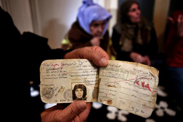Un membre de sa famille montre les papiers de Laila Saleh (en arrière-plan) , à Athènes, le 15 décembre 2017 [ARIS MESSINIS / AFP]