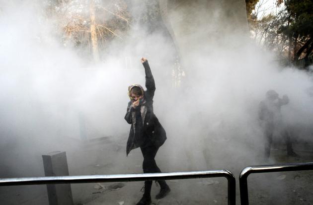 Une Iranienne dans la fumée de gaz lacrymogène lors de manifestations à l'université de Téhéran, le 30 décembre 2017 [STR / AFP]