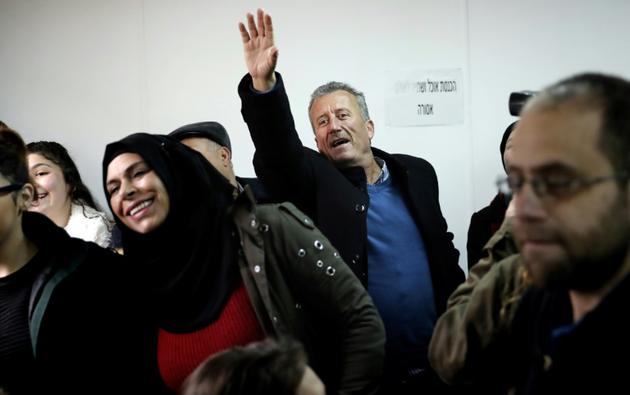 Photo du père d'Ahed Tamimi, Bassem (C), saluant sa fille de la main lors de l'ouverture du procès de la jeune palestinienne le 13 février 2018 devant le tribunal militaire d'Ofer, en Cisjordanie occupée [THOMAS COEX / AFP]