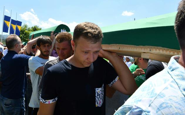 Des musulmans bosniaques, survivants du massacre de Srebrenica, en compagnie de visiteurs, transportent des restes de victimes du massacre, 11 juillet 2017 au mémorial de Potocari, près de Srebrenica, avant leurs funérailles [ELVIS BARUKCIC / AFP]