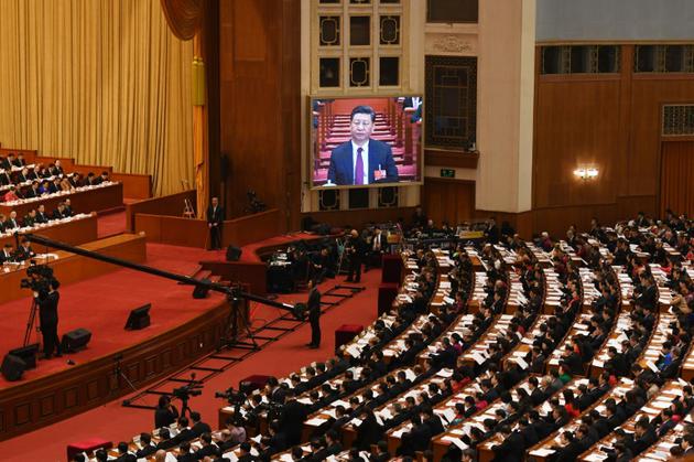 Le président chinois Xi Jinping apparait en direct sur un écran au dessus des délégués pendant le discours du Premier ministre Li Keqiang lors de l'ouverture de la session annuelle du Parlement, à Pékin le 5 mars 2018  [GREG BAKER / AFP]