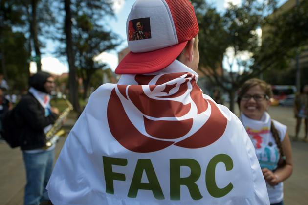Un militant des Farc enveloppé dans un drapeau avec un logo du nouveau parti politique "révolutionnaire" à Bogota, le 1er septembre 2017 [Raul Arboleda / AFP]