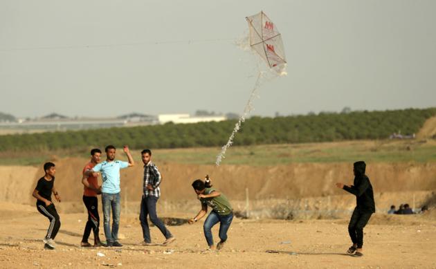 Des jeunes Palestiniens tentent de faire s'envoler un cerf-volant auquel est attaché un cocktail Molotov, le 18 avril 2018 près de la frontière entre la bande de Gaza et Israël [MAHMUD HAMS / AFP]