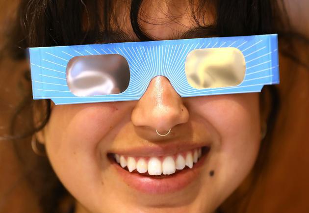 Karolyna Landin, employée de Warby Parker, pose avec une paire de lunettes de protection spéciales éclipse dans la boutique où elle travaille le 11 août 2017 à New York [SPENCER PLATT / GETTY IMAGES NORTH AMERICA/AFP/Archives]