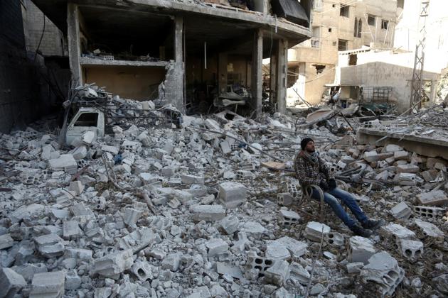 Un homme est assis au milieu des décombres dans la ville de Hammouriyé, dans la partie rebelle de la Ghouta orientale,le 9 mars  2018 [ABDULMONAM EASSA / AFP]