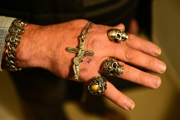 Un fan montre ses bijoux, des copies de ceux portés par son idole Johnny Hallyday, devant la maison du chanteur à Marne-la-Coquette, le 6 décembre  2017 [NICOLAS TUCAT / AFP]