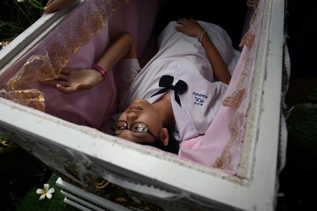 Une adolescente thaïlandaise s'allonge dans le cercueil du "café de la mort", à Bangkok, le 30 mars 2018 [LILLIAN SUWANRUMPHA / AFP]