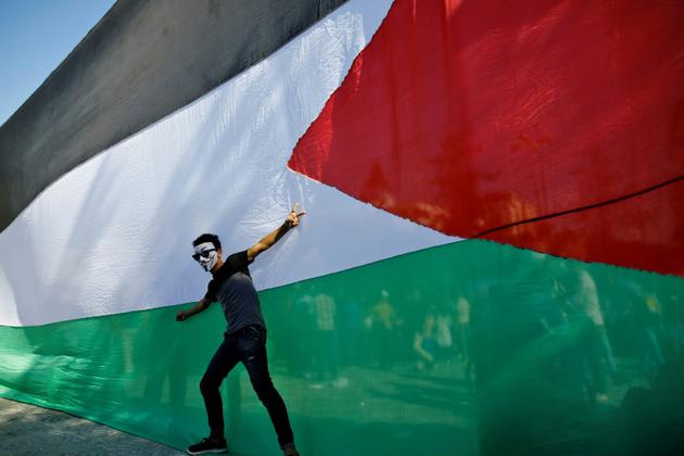 Un jeune homme pose devant le drapeau palestinien le 12 octobre 2017 dans la ville de Gaza [MOHAMMED ABED / AFP/Archives]