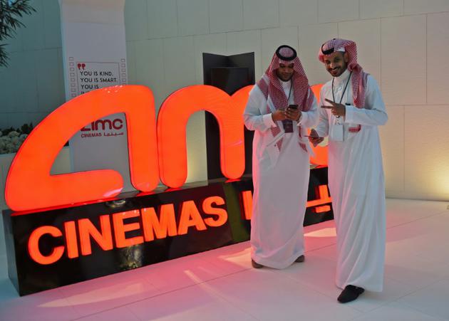 Des Saoudiens posent devant le logo du géant américain AMC Entertainment, première société autorisée à exploiter des cinélas eb Arabie saoudite, le 18 avril 2018 à Ryad [Fayez Nureldine / AFP]