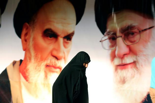 Photo d'une Iranienne passant devant un portrait du guide suprême, l'Ayatollah Ali Khamenei (D), et du fondateur de la République islamique, l'Ayatollah Ruhollah Khomeini (G), le 1er février 2015 près de Téhéran [ATTA KENARE / AFP/Archives]