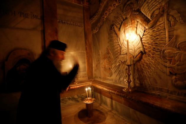 Un ecclésiastique dans le tombeau où le Christ a été enterré selon la tradition, dans l'église du Saint-Sépulcre à Jérusalem, le 21 mars 2017 [Gali TIBBON / AFP]
