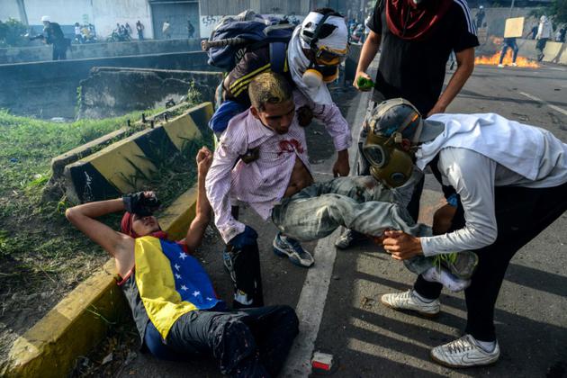 Des manifestants secourent des blessés après des heurts avec les forces de l'ordre vénézuéliennes, le 31 mai 2017 à Caracas [FEDERICO PARRA / AFP]