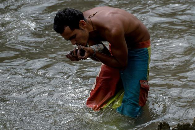Un Vénézuélien trie les débris charriés par le courant du fleuve Guaire, le 1er février 2018 [FEDERICO PARRA / AFP/Archives]