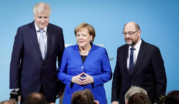 La chancelière allemande Angela Merkel, entourée du leader de la CSU Horst Seehofer (G), et du leader du SPD Martin Schulz, lors d'une conférence de presse à Berlin le 12 janvier 2018 [Kay Nietfeld / dpa/AFP]