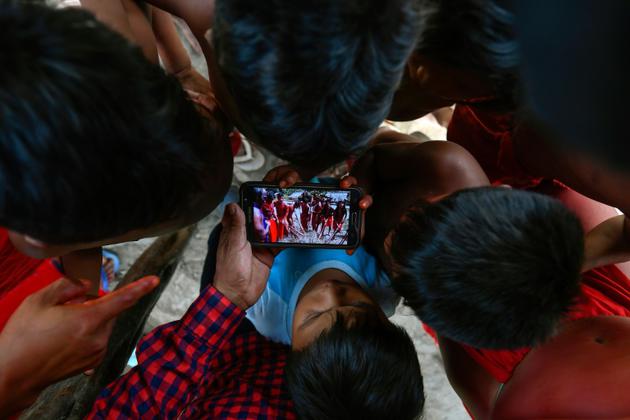 Des enfants de la tribu Waiapi regardent sur un smartphone une vidéo d'une danse traditionnelle Waiapi, dans leur village de Manilha le 12 octobre 2017 [Apu Gomes / AFP]