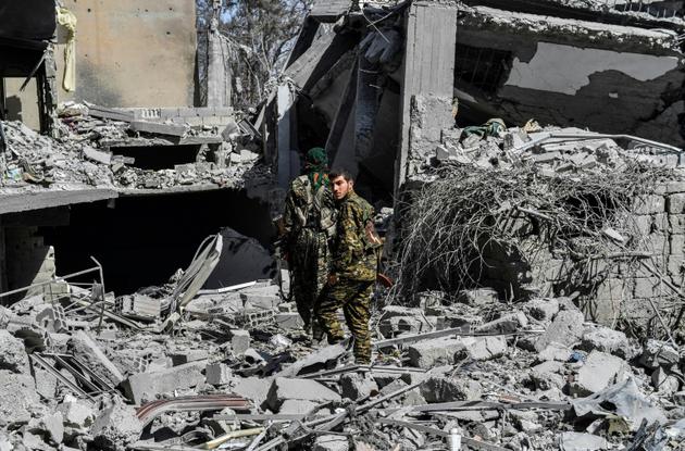 Des combattants des Forces démocratiques syriennes au milieu des décombres d'immeubles démolis, le 8 octobre 2017 à Raqa [BULENT KILIC / AFP]