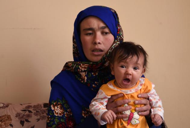 Jahantab Ahmadi, une Afghane déterminée à faire des études dont la photo a ému tout le pays, avec son plus jeune enfant lors d'un entretien avec l'AFP à Kaboul, 24 mars 2018 [WAKIL KOHSAR / AFP]