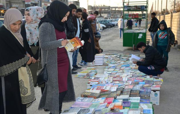 Des Irakiens vendent et achètent des livres sur un trottoir de Mossoul, dans le nord de l'Irak, le 12 janvier 2018 [Ahmad MUWAFAQ / AFP]