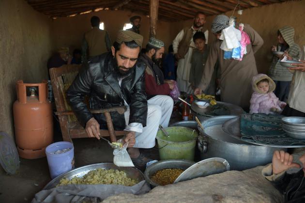 Des réfugiés afghans servent de la nourriture à d'autres réfugiés dans un camp près d'Islamabad, le 19 janvier 2018 [AAMIR QURESHI / AFP]
