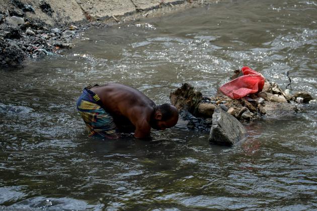 Au péril de leur vie, des Vénézuélien fouillent les eaux sales du fleuve Guaire, le 1er février 2018 [FEDERICO PARRA / AFP/Archives]