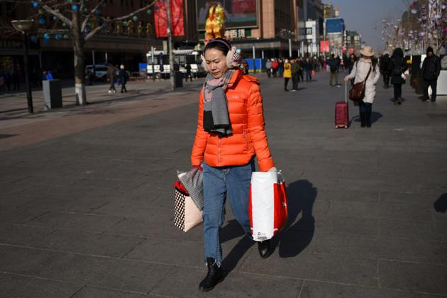 Une femme marche dans une rue commerciale à Pékin, le 18 janvier 2018 [WANG ZHAO / AFP]