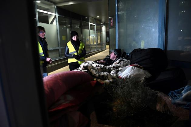 Des volontaires des Restos du Coeur parlent avec un sans-abri à Strasbourg, où la température est descendue à -7 degrés en soirée le 26 février 2018 [FREDERICK FLORIN / AFP]