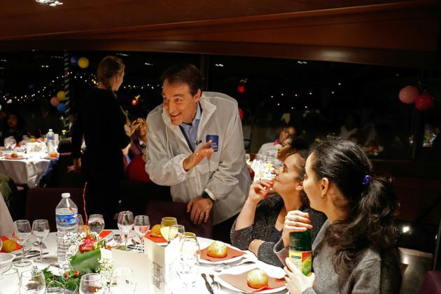 Bernard Thibaud, secrétaire général du Secours Catholique, avec des invités lors d'une croisière caritative annuelle sur la Seine à Paris, le 24 décembre 2017 [FRANCOIS GUILLOT / AFP]