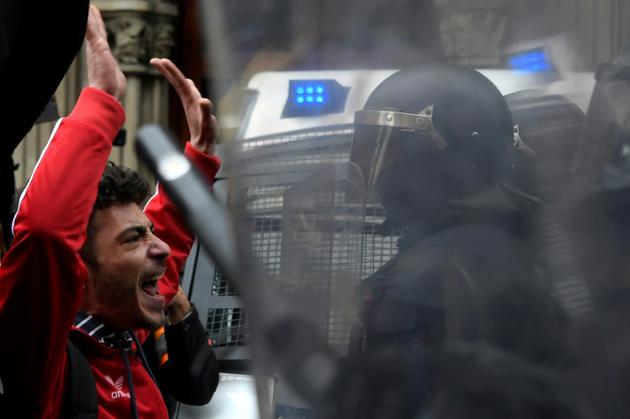 Un manifestant à Barcelone le 25 mars 2018 qui proteste contre l'arrestation de Carles Puigdemont en Allemagne à la demande de la justice espagnole, face à la police anti-émeutes [LLUIS GENE / AFP]